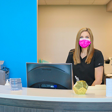 A friendly receptionist wearing a mask at Singing River Dentistry